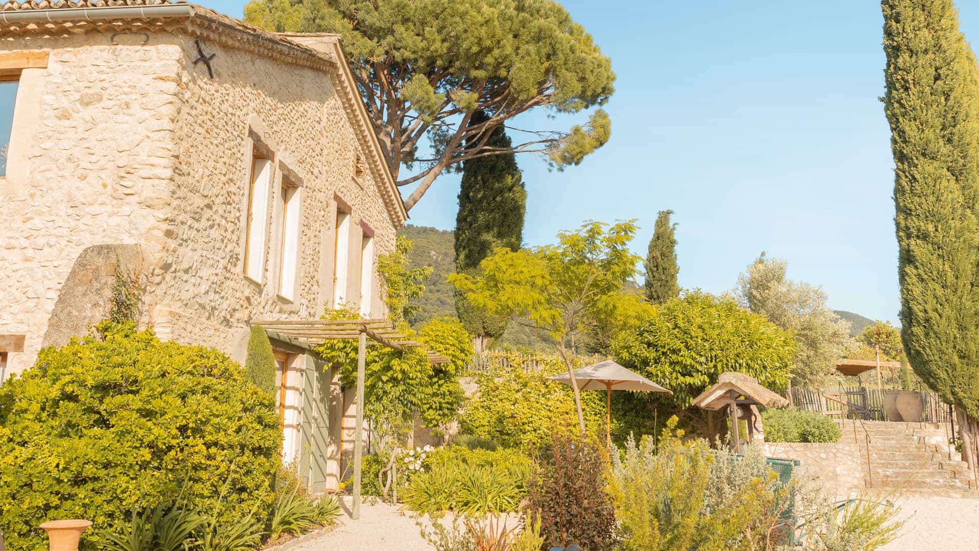 A gravel courtyard with a cypress tree at a stone house in the South of France